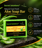 A green and black bar of Secret Solutions Natural Cool Fresh Aloe Soap Bar is displayed on a dark textured surface with fresh aloe vera slices. The background is dark green with text highlighting benefits such as deep cleansing, excess oil removal, and fresh aloe care.
