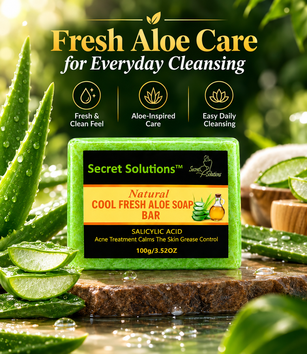 A bar of Secret Solutions Natural Cool Fresh Aloe Soap Bar is displayed on a stone slab surrounded by fresh aloe vera slices and leaves in a lush, green outdoor setting. The product packaging is green with black and orange panels, and the background is a soft-focus green garden with text overlays reading 'Fresh Aloe Care for Everyday Cleansing'.